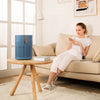 Dame in woonkamer met AirExchange 150‑T, fluisterstille luchtreiniger, voor schone lucht en betere slaap, blauw