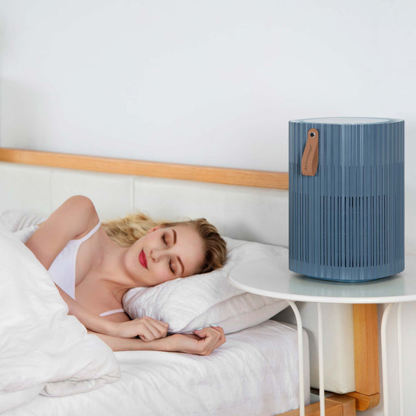 Dame slapend in bed met AirExchange 150‑T, fluisterstille luchtreiniger voor in de slaapkamer, voor schone lucht en betere slaap, blauw